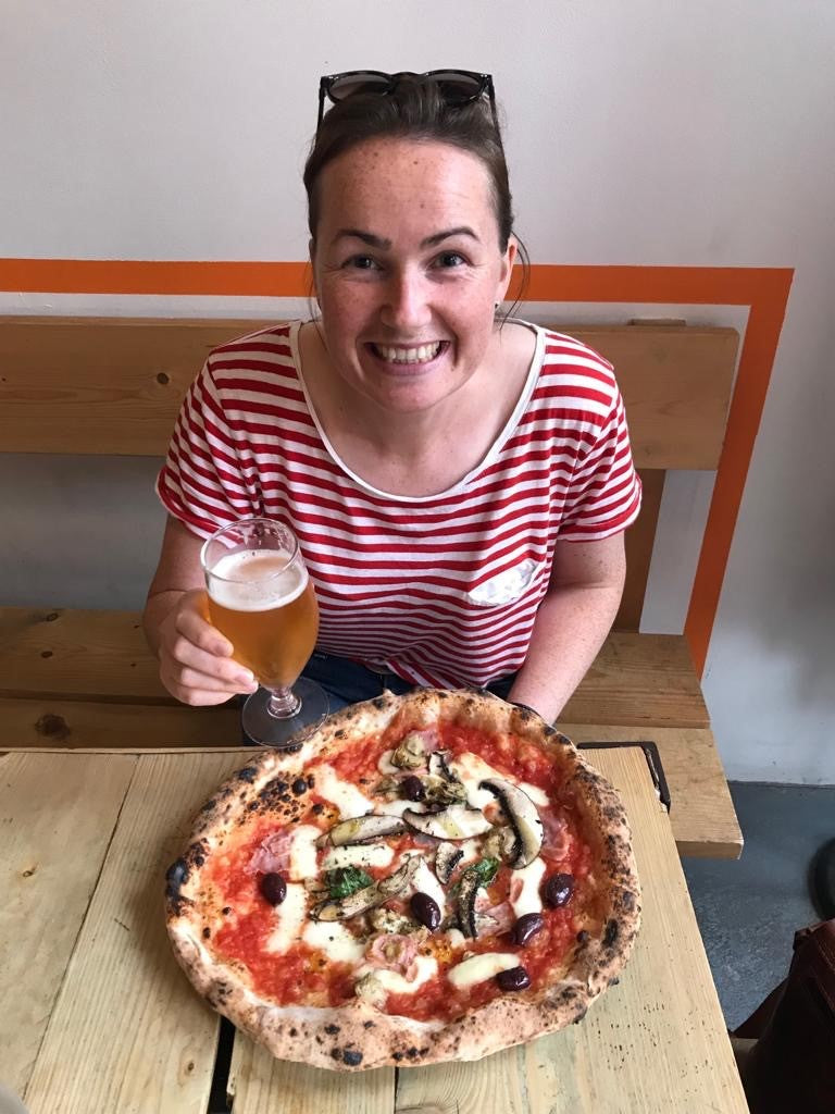 Photograph of Nicola, enjoying a delicious looking pizza and pint